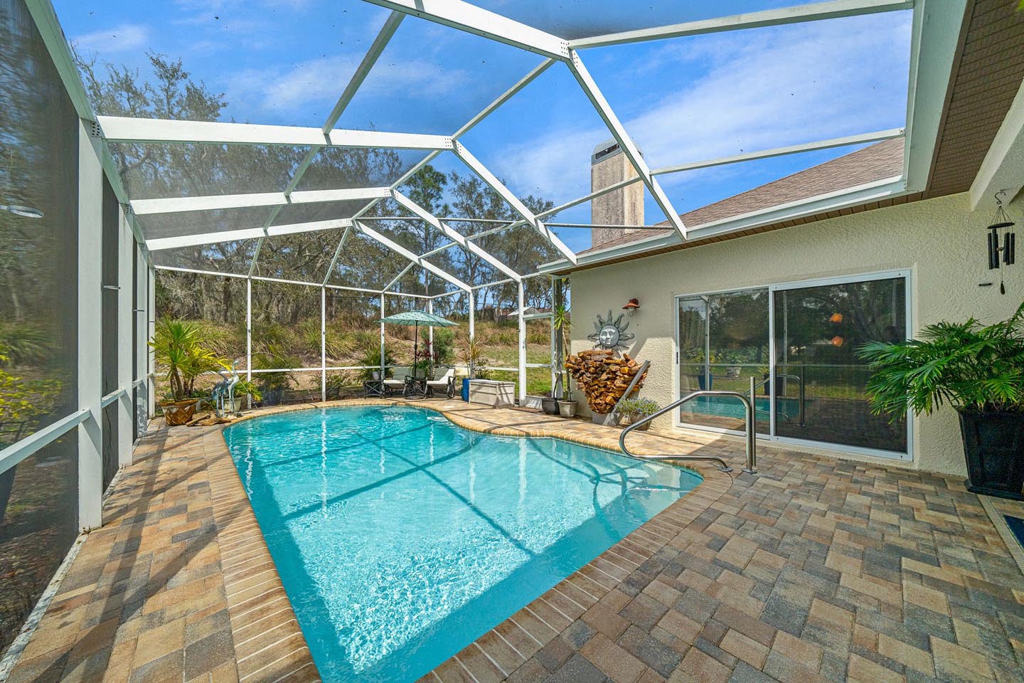 real estate photo of a screened in pool with patio